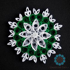 a green and white paper snowflake sitting on top of a black surface