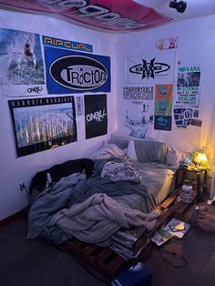 a bedroom with posters on the wall and an unmade bed