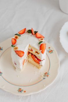 a piece of cake with white frosting and sliced strawberries on the top is sitting on a plate