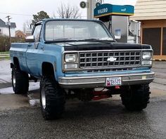 a blue truck parked in front of a gas station