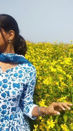 a woman is standing in a field full of yellow flowers and holding out her hand