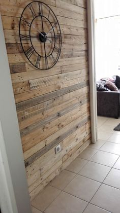 a large clock mounted to the side of a wooden wall next to a couch in a living room