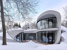 an unusual house is surrounded by snow and trees