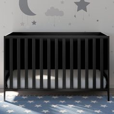 a baby crib with stars and moon decals on the wall