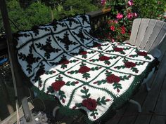 a blanket that is sitting on top of a wooden bench in front of some flowers