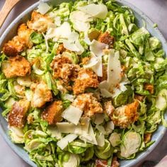 a bowl filled with shaved lettuce and croutons topped with parmesan cheese