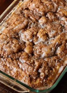 a casserole dish with cinnamon rolls and icing on it sitting on a wire rack