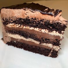 a slice of chocolate cake with frosting on a white plate, ready to be eaten