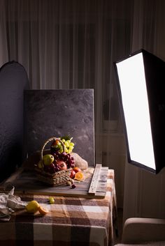 a table topped with a basket of fruit next to a light