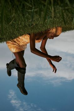 a man is hanging upside down from the grass on top of his head and feet