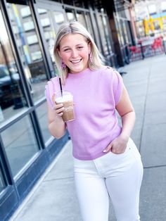 Blonde headed smiling young woman walking in an urban area carrying a iced coffee beverage and wearing a lilac sleeveless sweater with shoulder details including pearlized buttons and also wearing white denim jeans. She is advertising the sweater and jeans for the online women's boutique Mom Buns and Ruffles. Gathered Fabric, Flattering Jeans, Spring Sweater, Purple Shirt, Brunch Outfit