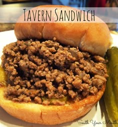 a sloppy joe sandwich sitting on top of a white plate next to a pickle