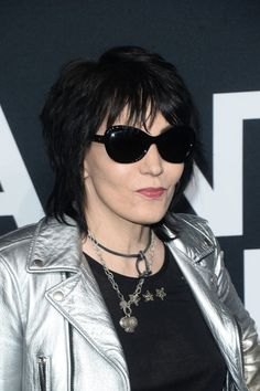 a woman with black hair wearing sunglasses and a silver jacket