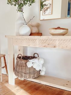 a basket sitting on top of a wooden table next to a vase with flowers in it