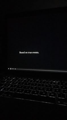 an open laptop computer sitting on top of a black table in the dark with text reading based on true events