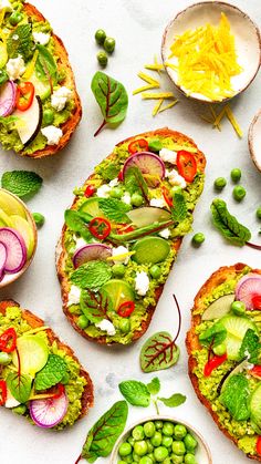 several slices of bread topped with veggies and other toppings next to bowls