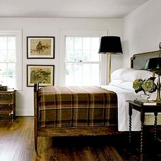 a bedroom with white walls and wood floors, two lamps on either side of the bed