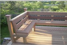 a wooden bench sitting on top of a wooden deck next to a lush green hillside