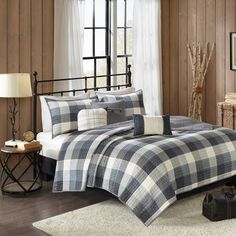 a bed room with a plaid comforter and pillows