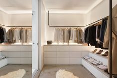 an open closet with clothes and shoes on display in the center, along with white walls