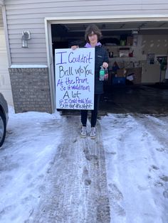 a woman standing in front of a garage holding a sign