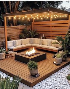 a fire pit in the middle of a wooden deck surrounded by potted plants and lights