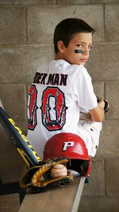 a young boy sitting on top of a bench wearing a baseball uniform and holding a bat