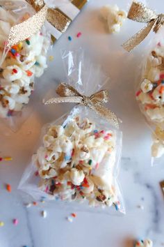 three bags filled with popcorn and sprinkles on top of a white table