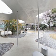 an empty courtyard with benches and trees in the background, surrounded by graveled walkways