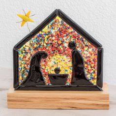 two black cats standing in front of a house made out of sprinkles