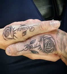 two people with matching tattoos on their fingers, one holding the other's hand