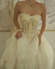 a woman in a white wedding dress with a necklace and ring on her left hand