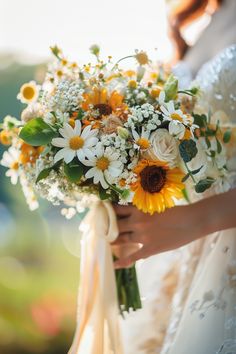 a bride holding a bouquet of sunflowers and daisies