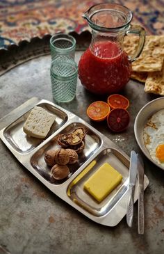 an assortment of food is on a tray with utensils and glass jugs