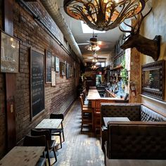 the interior of a restaurant with wooden tables and chairs, exposed brick walls, and deer antlers hanging from the ceiling