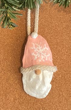 a christmas ornament hanging on a tree branch with snowflakes and a hat