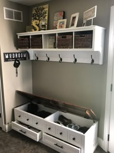 a white bench with two drawers and baskets on the wall above it, along with other storage bins