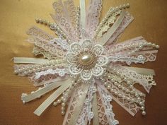 a white lace flower with pearls and beads on the center is sitting on a brown surface