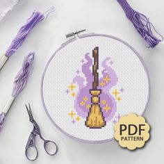 a cross stitch pattern with scissors, thread and needle on the white table next to it