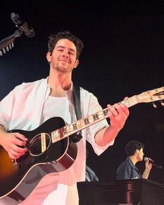 a man playing an acoustic guitar on stage