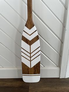 a wooden paddle on the floor next to a white wall and wood paneled door