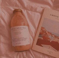 a bottle of tea sitting on top of a bed next to a book