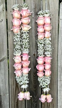 pink roses and baby's breath hanging from a wooden fence with white flowers on it