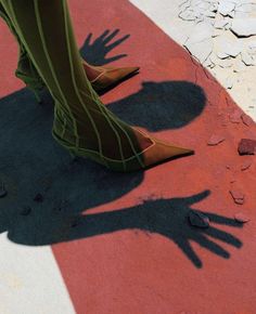 the shadow of a person's legs and hand on a red carpet