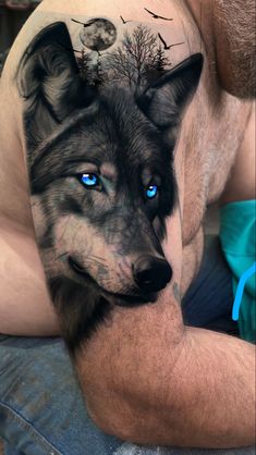 a man with blue eyes and tattoos on his arm is laying down next to a dog