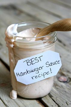 a jar filled with sauce sitting on top of a wooden table next to a spoon