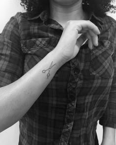 a woman with a tattoo on her left arm holding a pair of scissors in her right hand