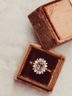 an engagement ring sits in a velvet box on the floor next to it's packaging