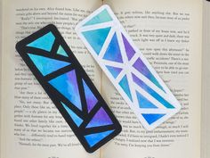 two bookmarks sitting on top of an open book with blue and purple geometric designs