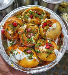 a person holding a plate full of food with sauces and toppings on it